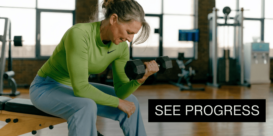An active woman over 40 training her arm muscles by lifting a heavy black dumbbell in a gym